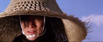 Movie still from “Shogun Assassin” (1980), directed by Kenji Misumi – A person wearing a straw hat and a helmet; Close Up shot, Low angle