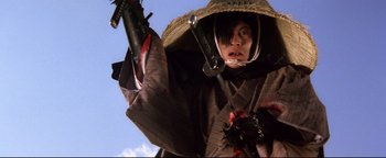 Movie still from “Shogun Assassin” (1980), directed by Kenji Misumi – A person in a hat and a suit holding a gun; Medium shot, Low angle