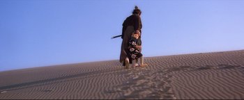 Movie still from “Shogun Assassin” (1980), directed by Kenji Misumi – Two people dressed in samurai garb walking in the sand; Wide shot, High angle