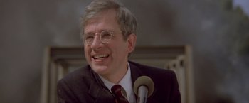 Movie still from “Short Circuit” (1986), directed by John Badham – An older man wearing a suit and tie; Close Up shot, Over the shoulder angle