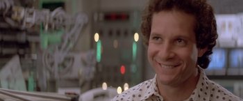 Movie still from “Short Circuit” (1986), directed by John Badham – A woman smiling for the camera in front of lights; Close Up shot, Over the shoulder angle