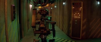 Movie still from “Short Circuit” (1986), directed by John Badham – A camera is set up to take a picture of a building; Wide shot, High angle