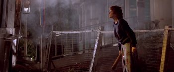 Movie still from “Short Circuit” (1986), directed by John Badham – A woman standing in front of a fence with a baseball bat; Wide shot, Low angle