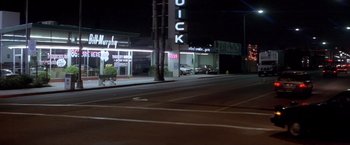 Movie still from “Short Circuit” (1986), directed by John Badham – A car parked on the side of the road near a building; Extreme Wide shot, High angle