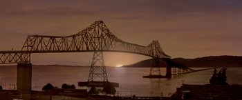 Movie still from “Short Circuit” (1986), directed by John Badham – A bridge that is over a body of water at sunset; Extreme Wide shot, Low angle