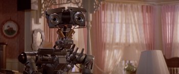 Movie still from “Short Circuit” (1986), directed by John Badham – The head of a robot in a living room; Close Up shot, Over the shoulder angle