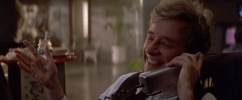 Movie still from “Short Circuit” (1986), directed by John Badham – A man talking on a phone while sitting in a chair; Close Up shot, Low angle