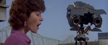 Movie still from “Short Circuit” (1986), directed by John Badham – A woman standing in front of a video camera; Close Up shot, Low angle