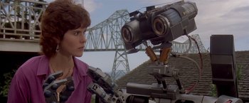 Movie still from “Short Circuit” (1986), directed by John Badham – A woman standing in front of a robot; Close Up shot, Low angle