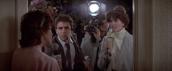 Movie still from “Short Circuit” (1986), directed by John Badham – A group of people standing next to each other holding microphones; Close Up shot, Over the shoulder angle