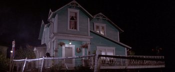 Movie still from “Short Circuit” (1986), directed by John Badham – A blue house with a wreath hanging on it's window; Wide shot, Low angle