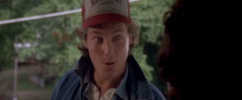 Movie still from “Short Circuit” (1986), directed by John Badham – A young man wearing a baseball cap and a denim jacket; Close Up shot, Over the shoulder angle