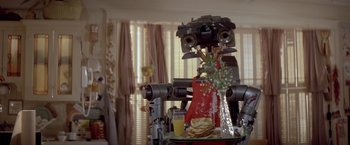 Movie still from “Short Circuit” (1986), directed by John Badham – An image of a robot in a living room setting; Medium shot, Low angle