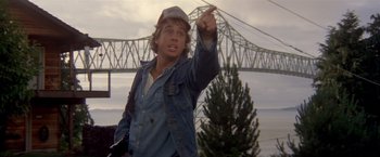 Movie still from “Short Circuit” (1986), directed by John Badham – A young man pointing to the sky in front of a bridge; Close Up shot, Low angle