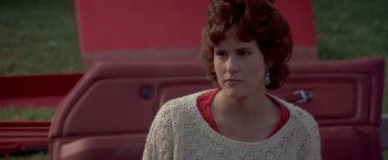 Movie still from “Short Circuit” (1986), directed by John Badham – A young woman with brown curly hair wearing a white sweater; Close Up shot, Over the shoulder angle