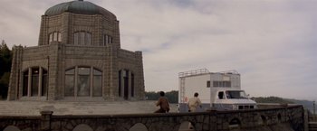 Movie still from “Short Circuit” (1986), directed by John Badham – Two people are walking on a bridge near a building; Extreme Wide shot, Low angle