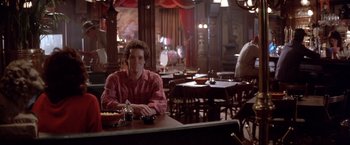 Movie still from “Short Circuit” (1986), directed by John Badham – A man sitting at a table in front of a plate of food; Wide shot, Over the shoulder angle