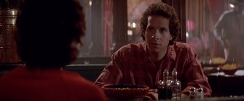 Movie still from “Short Circuit” (1986), directed by John Badham – A man sitting at a table in front of a bowl of food; Close Up shot, Over the shoulder angle