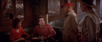 Movie still from “Short Circuit” (1986), directed by John Badham – Two men are sitting at a table in front of a plate of food; Medium shot, Over the shoulder angle