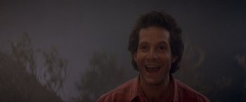 Movie still from “Short Circuit” (1986), directed by John Badham – A person smiling with trees in the background; Close Up shot, Low angle