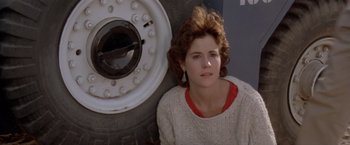 Movie still from “Short Circuit” (1986), directed by John Badham – A woman leaning up against a large tire; Close Up shot, Low angle