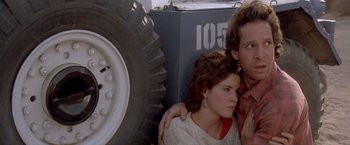 Movie still from “Short Circuit” (1986), directed by John Badham – A man and a woman sitting next to each other in front of a truck; Close Up shot, Low angle