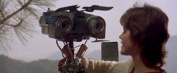 Movie still from “Short Circuit” (1986), directed by John Badham – A person is holding a video camera up to the camera; Close Up shot, Low angle