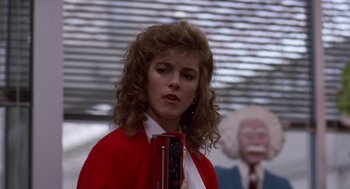 Movie still from “Short Circuit 2” (1988), directed by Kenneth Johnson – A woman in a red jacket is holding a camera; Close Up shot, Over the shoulder angle