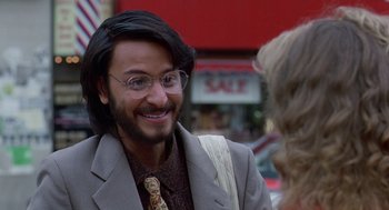 Movie still from “Short Circuit 2” (1988), directed by Kenneth Johnson – A man in a suit and tie with glasses and long hair; Close Up shot, Over the shoulder angle