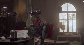 Movie still from “Short Circuit 2” (1988), directed by Kenneth Johnson – A robot sitting on top of a wooden table in a room; Wide shot, Low angle