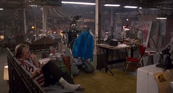 Movie still from “Short Circuit 2” (1988), directed by Kenneth Johnson – A man sitting on a motorcycle in a room with other people; Wide shot, High angle