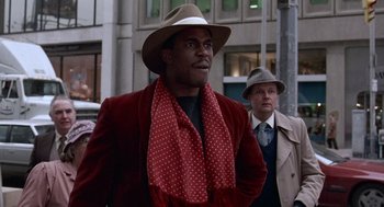 Movie still from “Short Circuit 2” (1988), directed by Kenneth Johnson – A man wearing a hat and a red jacket; Medium shot, Low angle