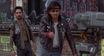 Movie still from “Short Circuit 2” (1988), directed by Kenneth Johnson – A man in a leather jacket pointing at the camera; Medium shot, Over the shoulder angle