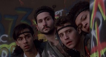 Movie still from “Short Circuit 2” (1988), directed by Kenneth Johnson – A group of young men standing next to each other in front of a wall; Close Up shot, Low angle