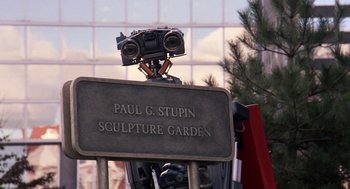 Movie still from “Short Circuit 2” (1988), directed by Kenneth Johnson – A statue with a camera on top of it; Extreme Close Up shot, Low angle