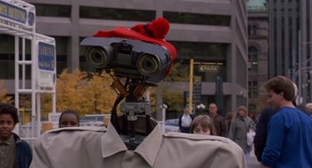 Movie still from “Short Circuit 2” (1988), directed by Kenneth Johnson – A robot with a red hat on top of it's head; Close Up shot, Low angle
