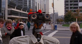 Movie still from “Short Circuit 2” (1988), directed by Kenneth Johnson – A robot with two eyes and two heads on top of it's head; Close Up shot, Over the shoulder angle