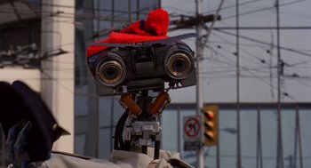Movie still from “Short Circuit 2” (1988), directed by Kenneth Johnson – A robot with a red hat on top of it's head; Close Up shot, Low angle