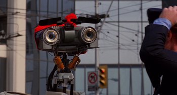 Movie still from “Short Circuit 2” (1988), directed by Kenneth Johnson – The head of a robot with a red bow; Close Up shot, Low angle