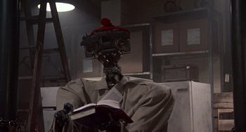 Movie still from “Short Circuit 2” (1988), directed by Kenneth Johnson – A robot is reading a book in a dark room; Close Up shot, Low angle