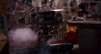 Movie still from “Short Circuit 2” (1988), directed by Kenneth Johnson – A camera on top of a tripod; Extreme Close Up shot, Low angle