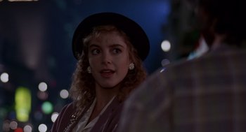 Movie still from “Short Circuit 2” (1988), directed by Kenneth Johnson – A woman wearing a black hat standing in front of lights; Close Up shot, Over the shoulder angle