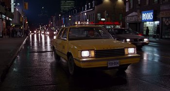Movie still from “Short Circuit 2” (1988), directed by Kenneth Johnson – A yellow taxi driving down a street at night; Wide shot, High angle