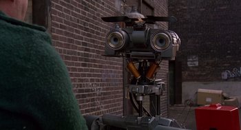 Movie still from “Short Circuit 2” (1988), directed by Kenneth Johnson – An image of an old fashioned camera on the side of a building; Close Up shot, Over the shoulder angle