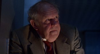 Movie still from “Short Circuit 2” (1988), directed by Kenneth Johnson – An older man wearing a suit and red tie; Close Up shot, Low angle
