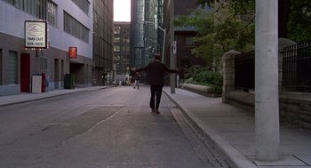Movie still from “Short Circuit 2” (1988), directed by Kenneth Johnson – A man walking down the street with his arms outstretched; Extreme Wide shot, High angle