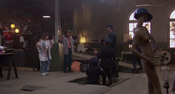 Movie still from “Short Circuit 2” (1988), directed by Kenneth Johnson – A group of people standing around a building; Wide shot, High angle
