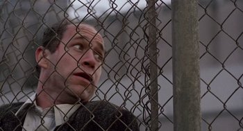 Movie still from “Short Circuit 2” (1988), directed by Kenneth Johnson – A man looking through a chain link fence; Close Up shot, Low angle