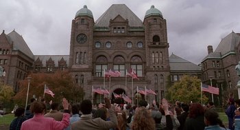 Movie still from “Short Circuit 2” (1988), directed by Kenneth Johnson – A crowd of people standing in front of a large building; Extreme Wide shot, High angle