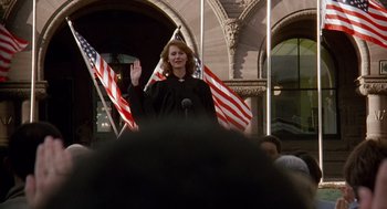 Movie still from “Short Circuit 2” (1988), directed by Kenneth Johnson – A woman in a black robe is holding a microphone; Medium shot, Low angle